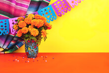 Day Of The Dead Dia De Los Muertos Celebration Background With Marigolds Or Cempasuchil Flowers In Vase And Papel Picado Decor. Bright Orange And Yellow Copy Space Traditional Mexican Culture Festival