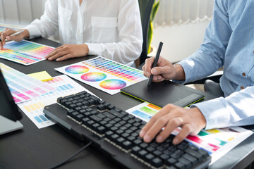 Poster - graphic designer or creative working together coloring using graphics tablet and a stylus at desk wi