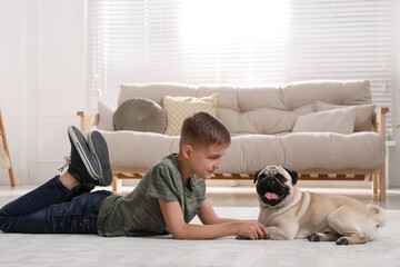 Wall Mural - Boy with his cute pug lying on floor in living room. Space for text