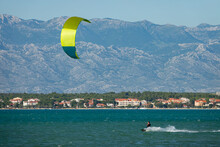 Man On Active Vacation In Croatia Kitesurfs Past A Coast Under The Velebit.