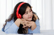 © Bangkok Click Studio - Asian young happy calm fat overweight woman lay down with happy smiling deep emotion peacefully while listening to music from big red earphones use playlist from black tablet at home in bedroom