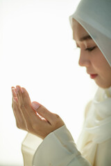 Wall Mural - Young and beautiful Asian Muslim woman rise hands and praying with respect and calm manner