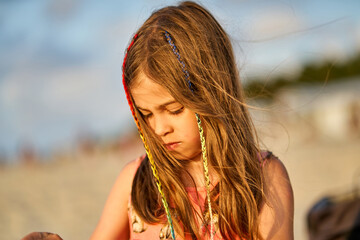 Wall Mural - Portrait of a happy little girl on the beach during sunset