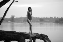 Monochrome Portrait Of Slender Woman In Bikini Standing On A Snag At The Lake