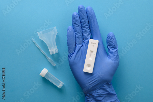 Hand in protective glove showing antigen covid test with pipette and saliva