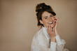 © Look! - Optimistic lady in white shirt smiling on isolated backdrop. Cool girl with sloppy hair and freckles looking into camera on beige backdrop..