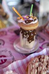 Sticker - Vertical closeup of a chocolate milkshake with a donut.