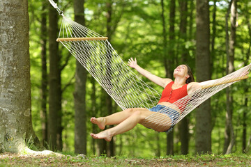 Wall Mural - Excited woman swinging on hammock celebrating vacation