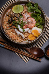 Wall Mural - Instant noodles with seafood tom yum, prawns, squid, mussels in a brown ceramic bowl