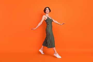 Sticker - Full length profile photo of joyful brunette millennial lady go wear overall sneakers isolated on orange background