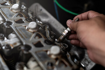 Wall Mural - Old Car spark plug in a hand of Technician remove and change in engine room blur background service concept