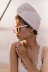 Wall Mural - Profile portrait of pretty blonde-haired girl with rays of setting sun on face in white outfit and stylish accessories