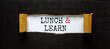 Lunch and learn symbol. Words 'Lunch and learn' appearing behind torn black paper. Beautiful black background. Business, educational and lunch and learn concept, copy space.