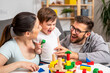 © lordn - Young happy family. Mother and father playing with her cute toddler son at home using didactic wooden toys. Home education