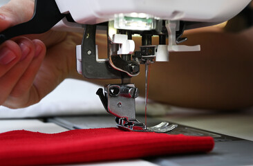 Wall Mural - Close up of a tailor working on a sewing machine.process of sewing clothes on sewing machine. Close-up of needle for sewing.