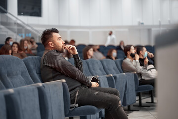 pensive man with a smartphone sitting in lecture hall.