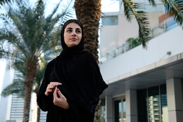 Smiling Modern Arab woman looking away with positive thoughts wearing hijab. Emirati on Abaya traditional clothing in the Middle East