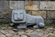 Stone lion. Located against the background of an old stone wall and paving stones.