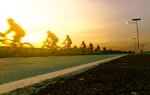 Blur Photo Sports Man Ride Bicycles With Speed Motion On The Road In The Evening With Sunset Sky. Summer Outdoor Exercise For Healthy And Happy Life. Cyclist Riding Mountain Bike On Bike Lane. Team.