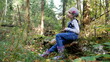 © Marina - A girl sits on a tree in the woods and dreams. The girl collects mushrooms. The girl dreams in the forest among the trees.
