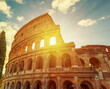 Colosseum or Flavian amphitheater against the background of an evening sunset with the sun in the arch