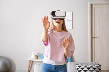 Wall Mural - Young woman with virtual reality glasses at home