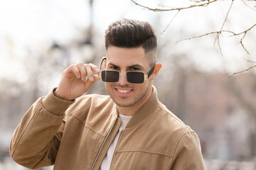 Wall Mural - Young man wearing stylish sunglasses outdoors