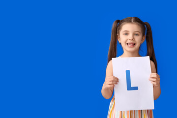 Little girl holding paper sheet with letter L on color background