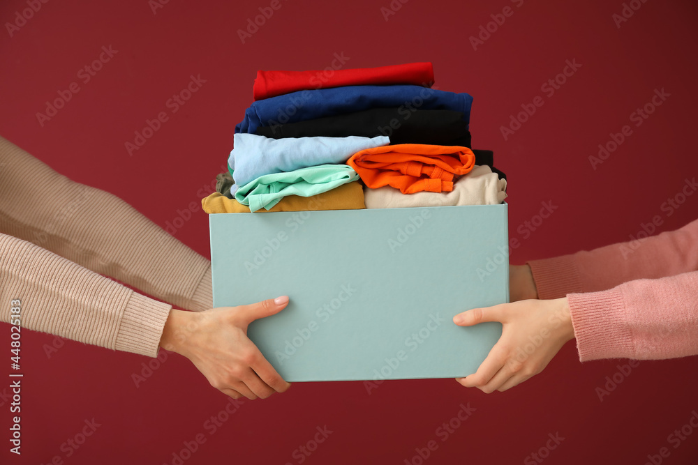 Women and wardrobe box with clothes on color background