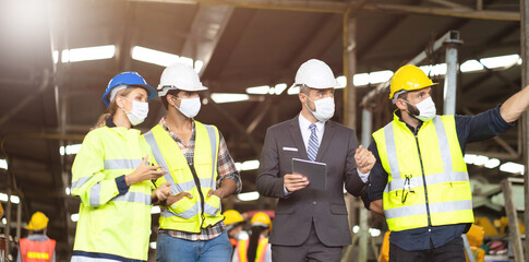 Engineers people are brainstorming solving problems of heavy industrial machinery. Worker man and asian woman wearing face mask prevent covid-19 virus and protective hard hat. .