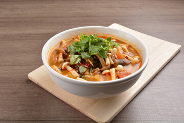 cook hot and spicy tom yum soup with mushroom and mixed vegetables in white bowl on wood background asian halal vegan menu