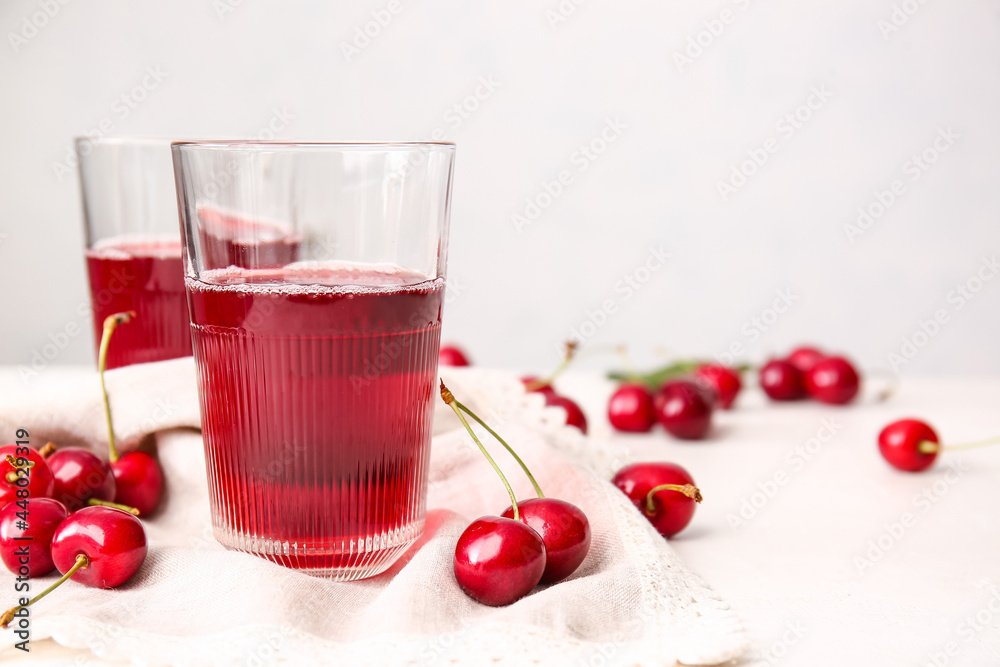 Glasses of sweet cherry wine on light background