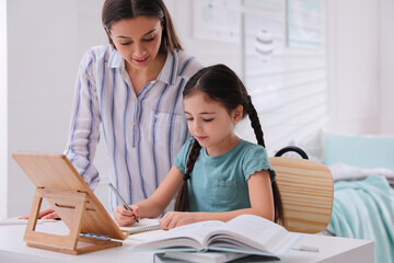 Canvas Print - Mother helping her daughter doing homework with tablet at home