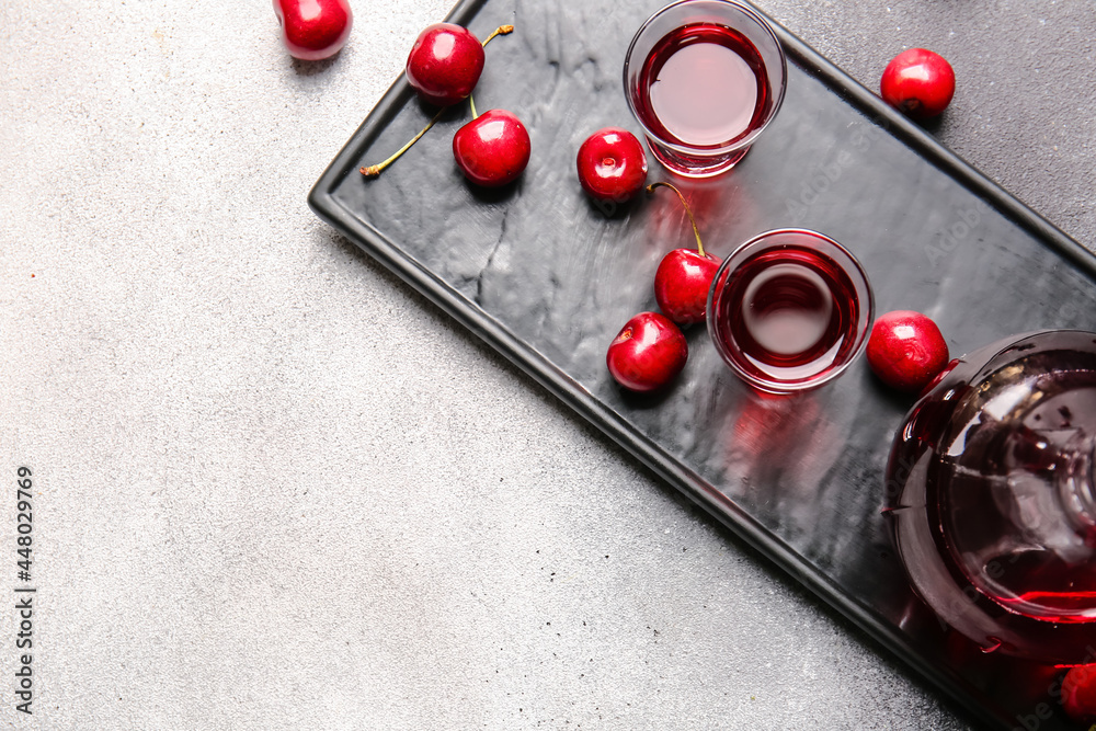 Glasses of sweet cherry wine on light background