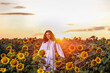 © czamfir - Beautiful woman enjoying nature in the sunflower field at sunset. Traditional clothes. Attractive brunette woman with long and healthy hair.