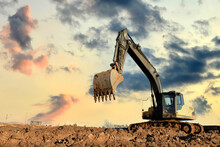 Excavator On Earthworks At Construction Site On Sunset Background. Heavy Machinery And Equipment For Earthmoving