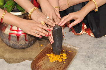 Wall Mural - Group of Indian women holding a stone piece of mortar sil batta for making turmeric paste for wedding ceremony. Its a rituals of traditional Hindu marriage which is known as Haldi ceremony