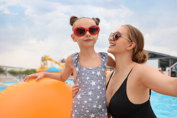 Poster - Mother and daughter with inflatable ring near pool in water park. Family vacation