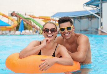 Wall Mural - Happy couple with inflatable ring in swimming pool at water park