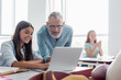 © LIGHTFIELD STUDIOS - Teacher looking at laptop near smiling schoolgirl in classroom