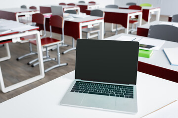 laptop with blank screen on desk in modern school