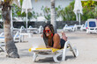 African American woman on the beach lying on a deck chair using a laptop