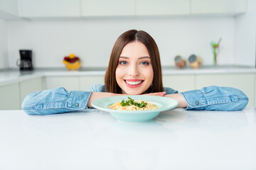 Wall Mural - Photo portrait girl smiling hungry near plate with pasta in the kitchen