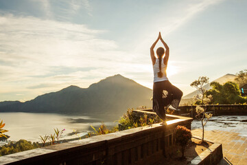 Wall Mural - Woman doing yoga at dawn near a volcano on the island of Bali