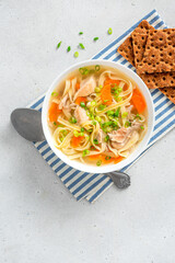 Sticker - Noodle soup. Homemade soup with chicken broth, carrots and noodles in a bowl on a gray concrete background top view. Free space for text. Delicious autumn or winter soup.