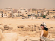 © tasslo.studio - Portrait of a caucasian woman in a hat overlooking Giza. A tourist admires the historical monuments on a hot day.
