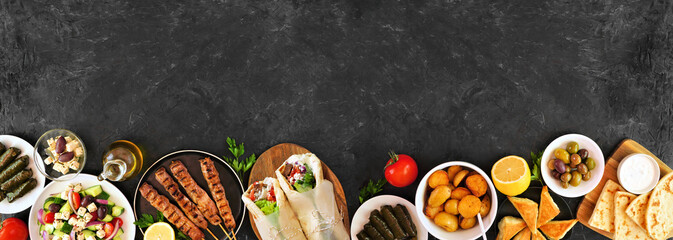 Poster - Greek food bottom border, top view on a dark banner background. Souvlaki, gyros wraps, salad, spanakopita, dolmades, pita and lemon potatoes. Copy space.