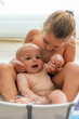 Caucasian girl bathing with her baby brother inside a portable bathtub.. Family concept. Caucasian ethnicity