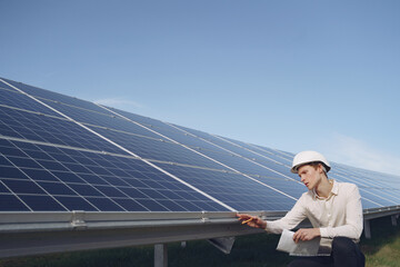 Wall Mural - Businessman in a white helmet near solar battery