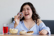 © Bangkok Click Studio - Happiness closeup shot of Asian young happy beautiful hungry overweight fat chubby female smile  hold chocolate donut in hand with dessert cake popcorn on table with happy and enjoy face